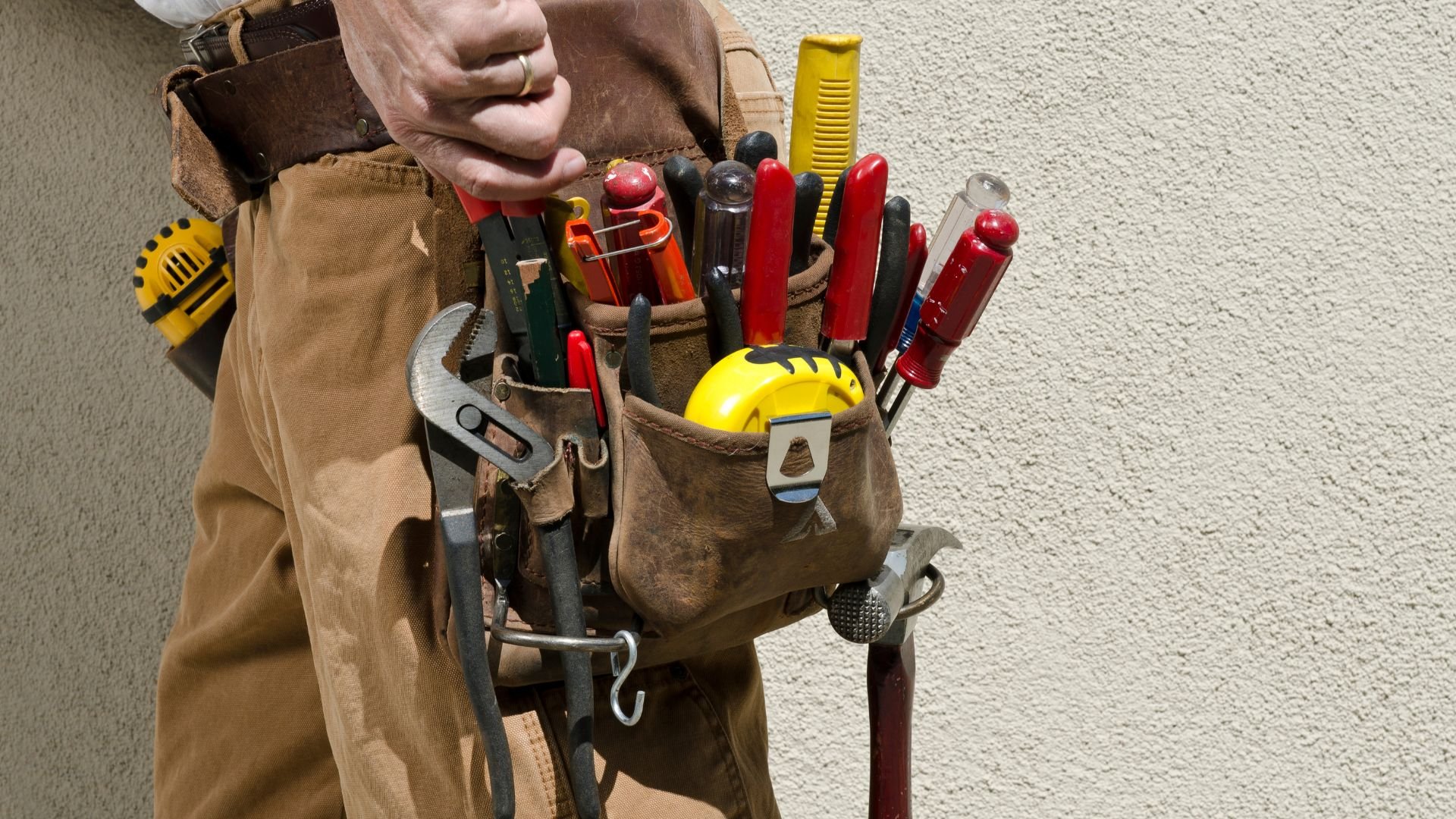 Tool belt filled with colorful screwdrivers, pliers, and safety helmet