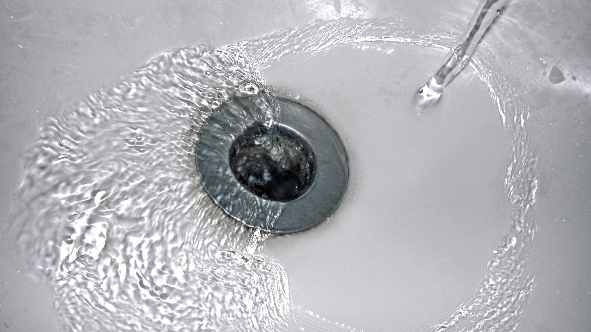 Water droplet creating rippling waves in a circular metallic surface