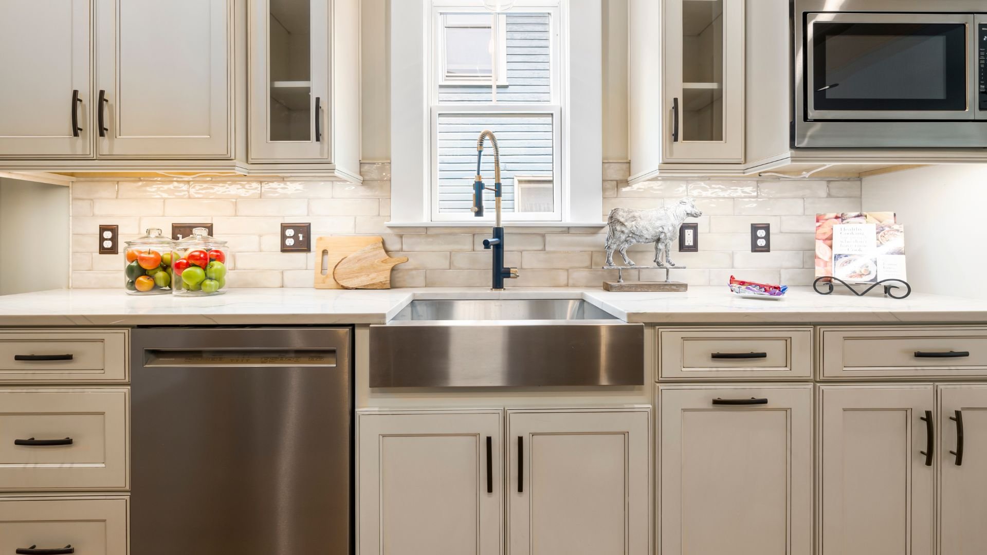 Modern kitchen with stainless steel appliances, white cabinets, and fruit jar