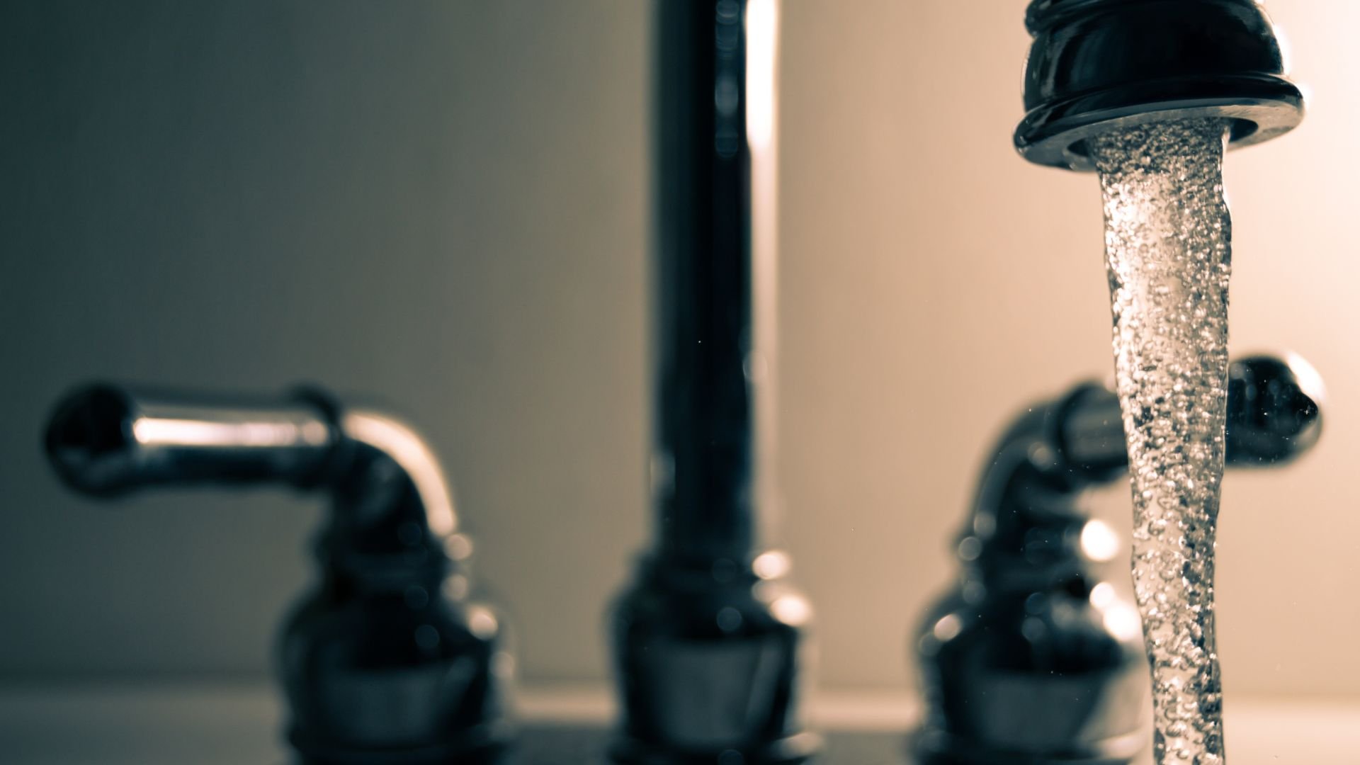 Water flowing from bathroom sink faucet with blurred handles