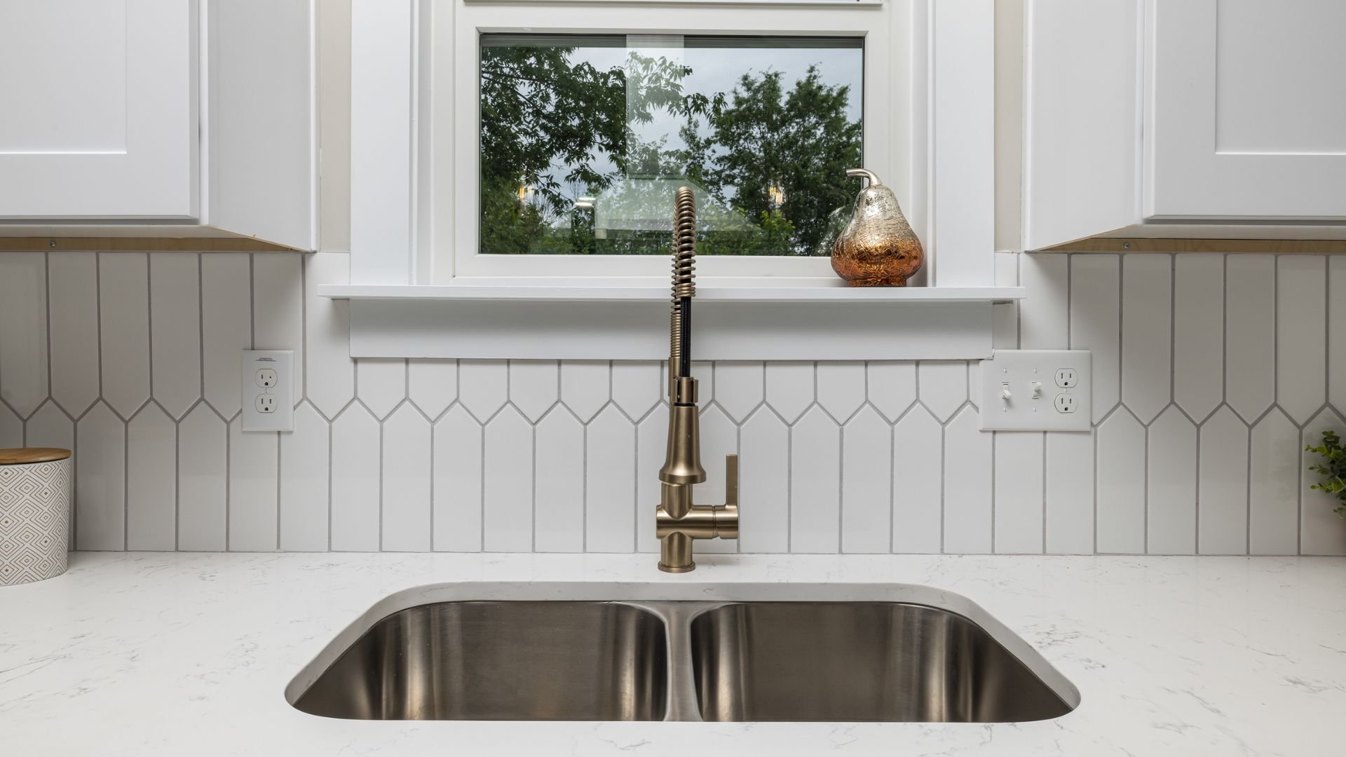 Modern kitchen sink with bronze faucet and white geometric tile backsplash