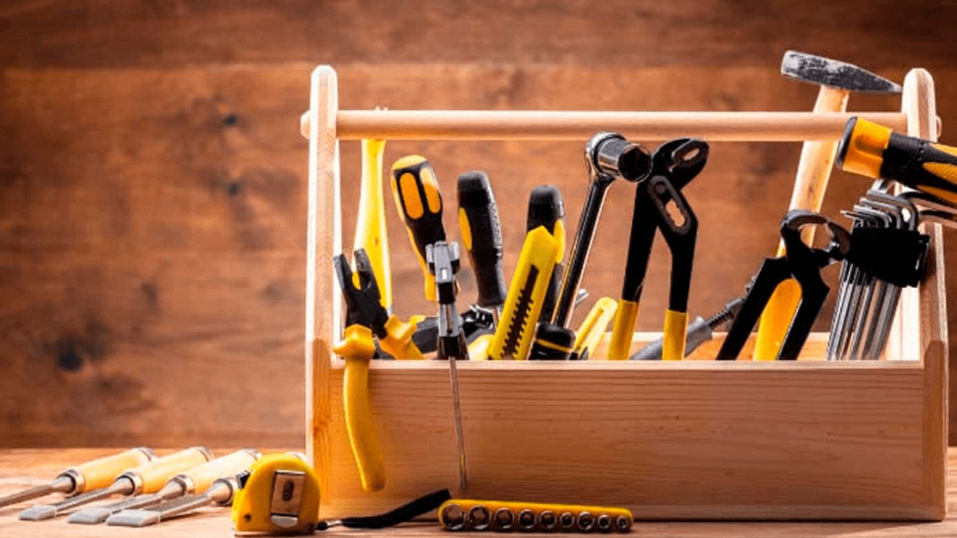 Wooden toolbox filled with yellow and black hand tools