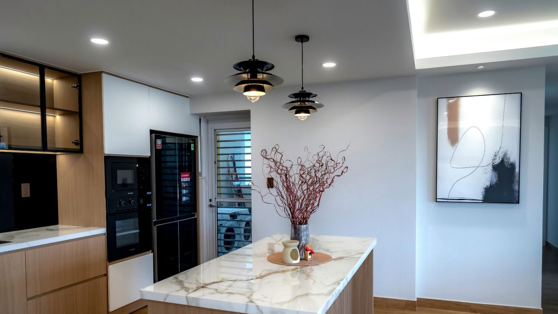 Modern kitchen with marble countertop, black appliances, and hanging pendant lights